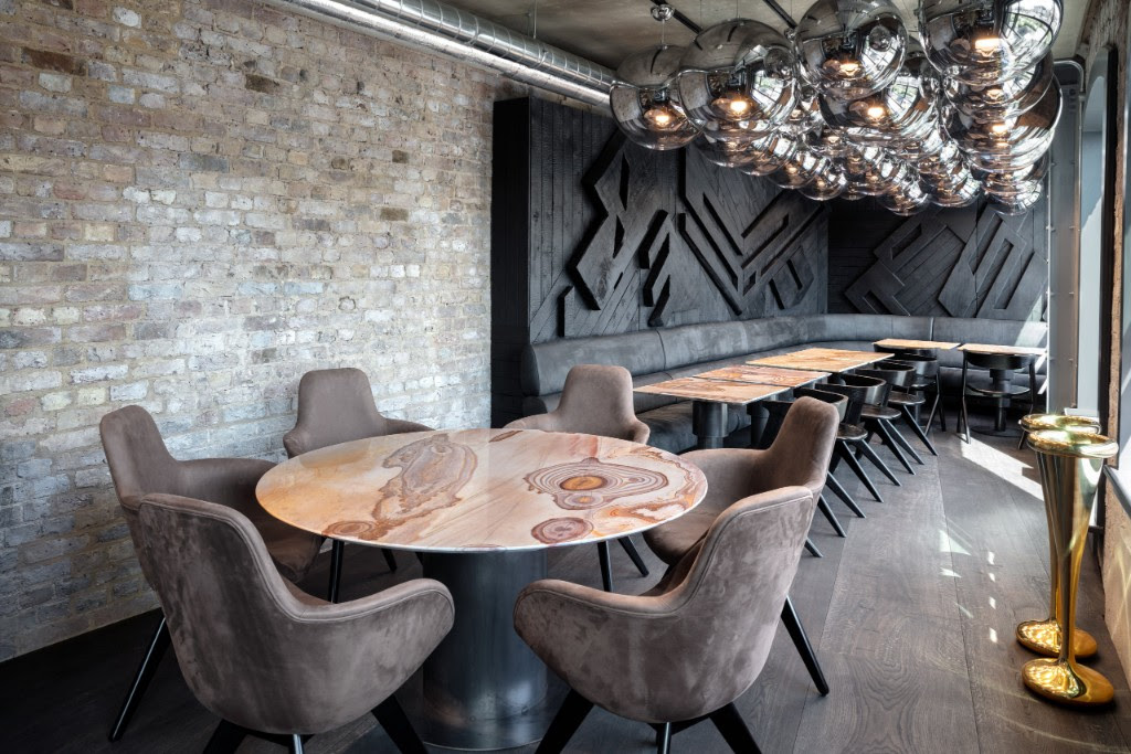 circular wood table with upholstered chairs inside Coal Office resturant in London