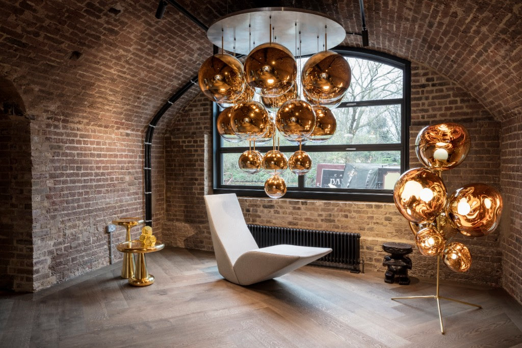 shiny metallic suspension lamps and tables inside brick gallery building