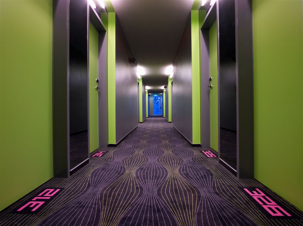 modern hotel hallway with neon green walls and black carpet