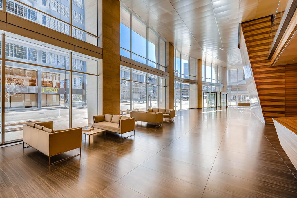 interior view of wood and stone office tower lobby with two-story-high glass windows