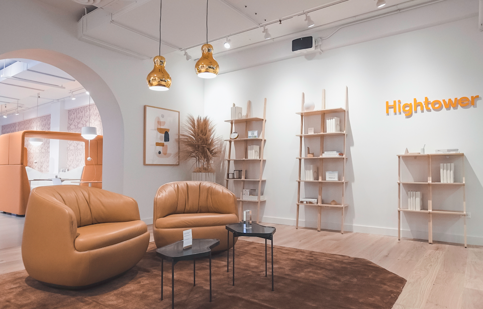 Hightower furniture showroom with simple wooden book shelves against white wall and leather swivel lounge chairs