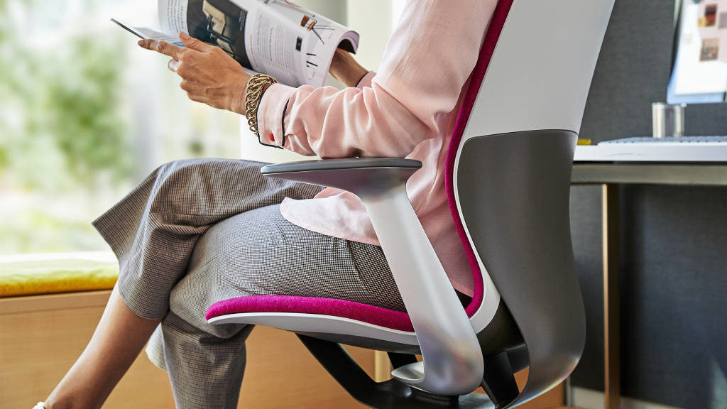 work chair with DesignTex Celliant upholstery backing. White shell with dark pink upholstery and woman sitting in chair 