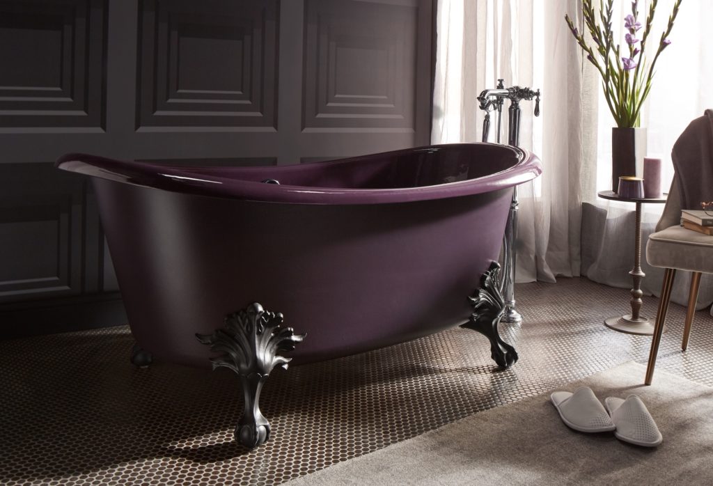 Kohler Shadows Collection black plum bathtub with ornate legs small table with vase and flowers and slippers on floor in foreground