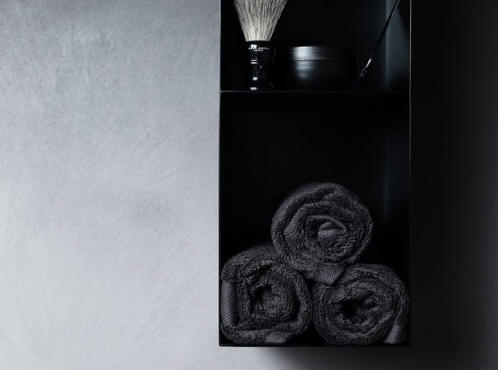 Atelier 12's Abisso Bathroom furniture wall unit in black lacquered wood open with shaving brush and towels