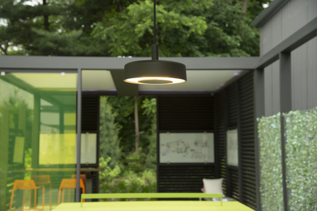 Motive Pendant in outdoor space with room visible behind with chairs and framed posters on teh walls