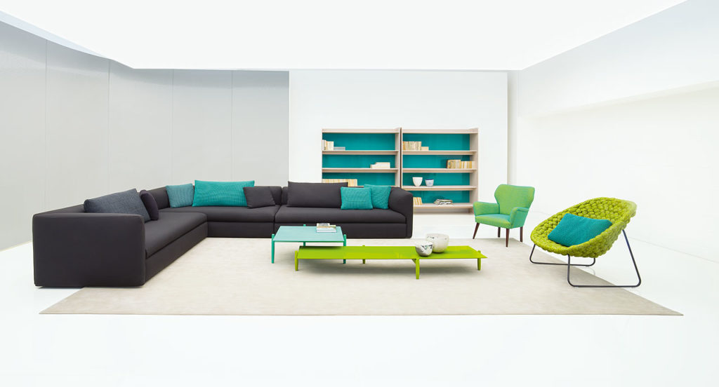 Paola Lenti Walt Seating two blue three-seat sofas joined at right angle with two low tables, two side chairs and a storage unit behind
