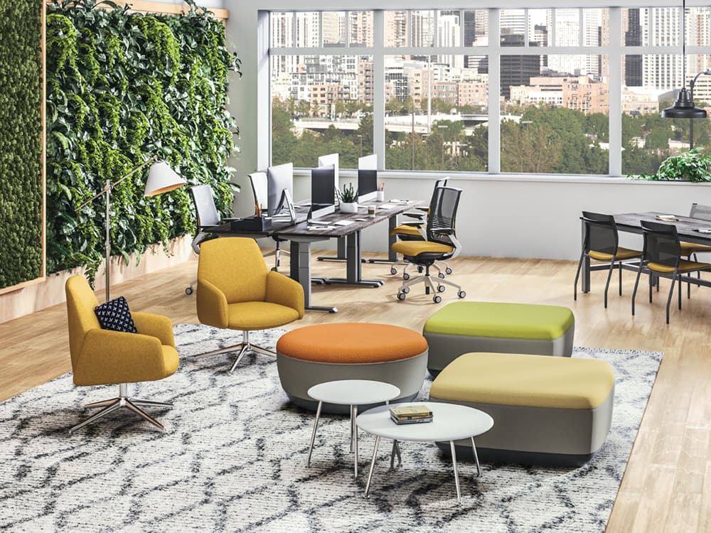 SitOnIt Envoi Lounge two mustard midback chairs in open office setting surrounded by workstations, chairs, ottomans, and low tables 