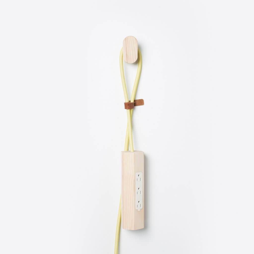 Most Modest's Niko power pendant with yellow cord hanging on Most Modest wall hook