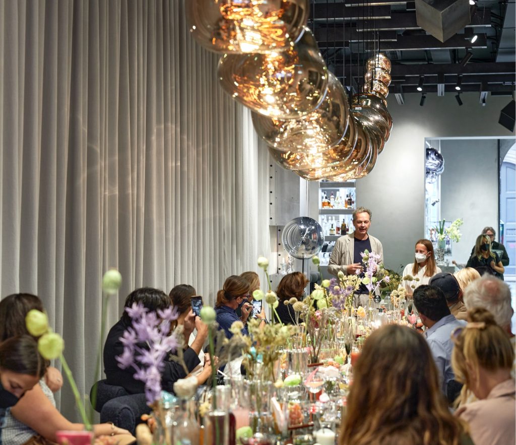 Tom Dixon in Milan Melt chandelier above table with fancy food and people