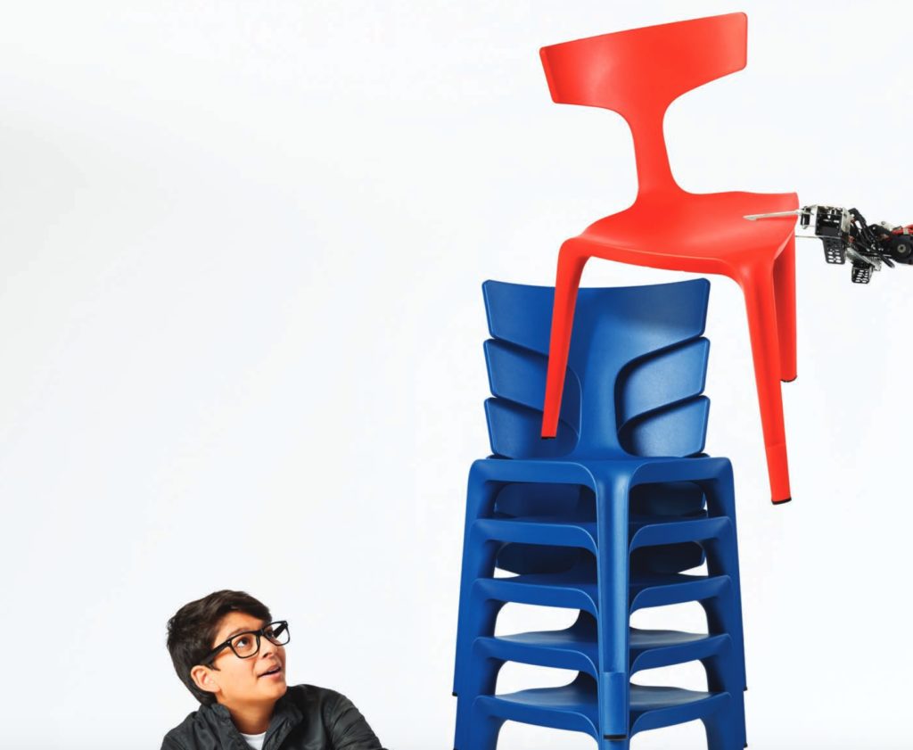 Stakki beign stacked blue chairs with one red and boy looking on 