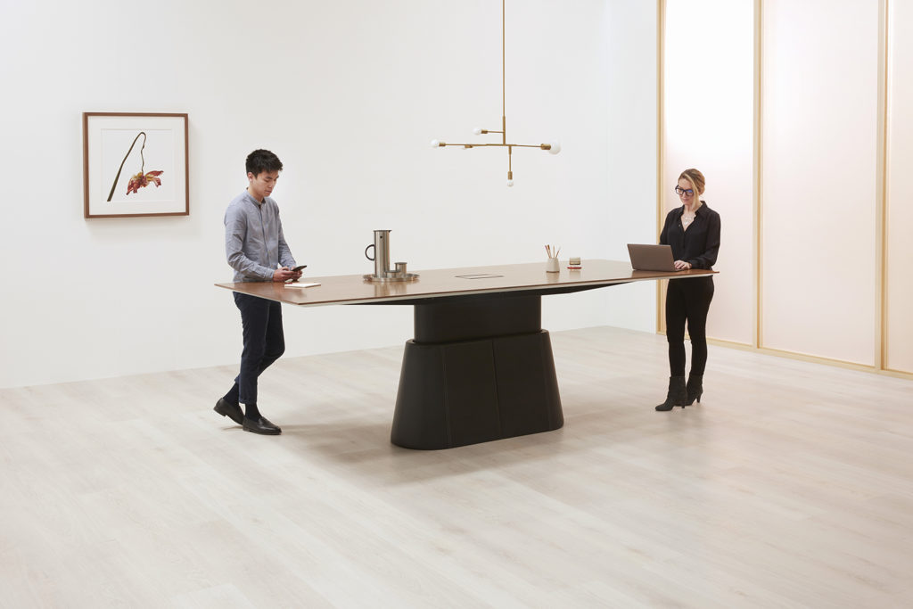 large sit-stand conference table with black base and two people working