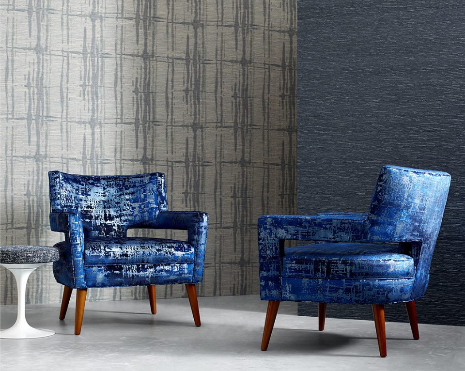 two chairs upholstered in metallic printed dark blue fabric alongside subtle patterned wallpapers