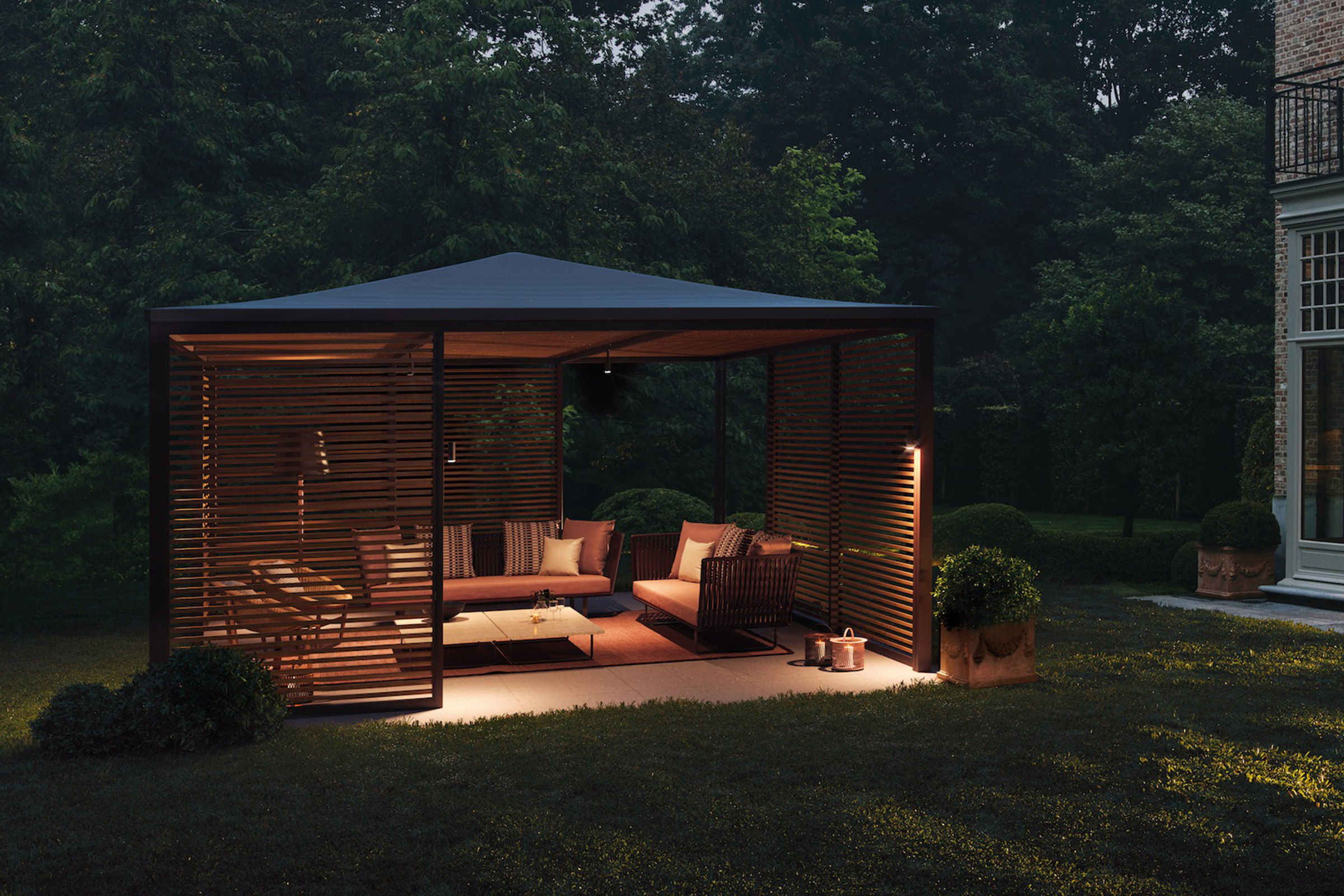 outdoor pergola at night with fabric roof and lounge furniture