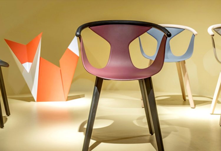 Image of four Pedrali Fox Chairs, three facing foward and one side view in black, rust, blue, and white with a fox sculpture in the background