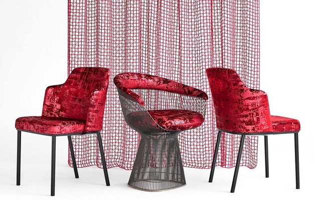two chairs upholstered in metallic red fabric in front of architectural lace curtain in red
