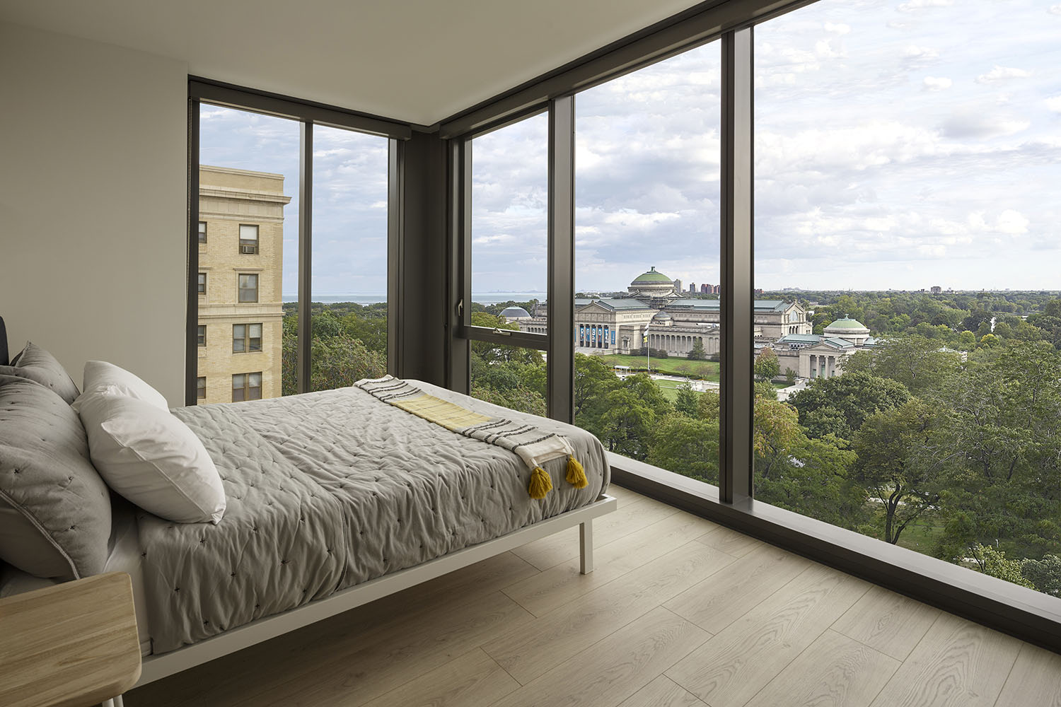 corner bedroom with two walls of windows and park view