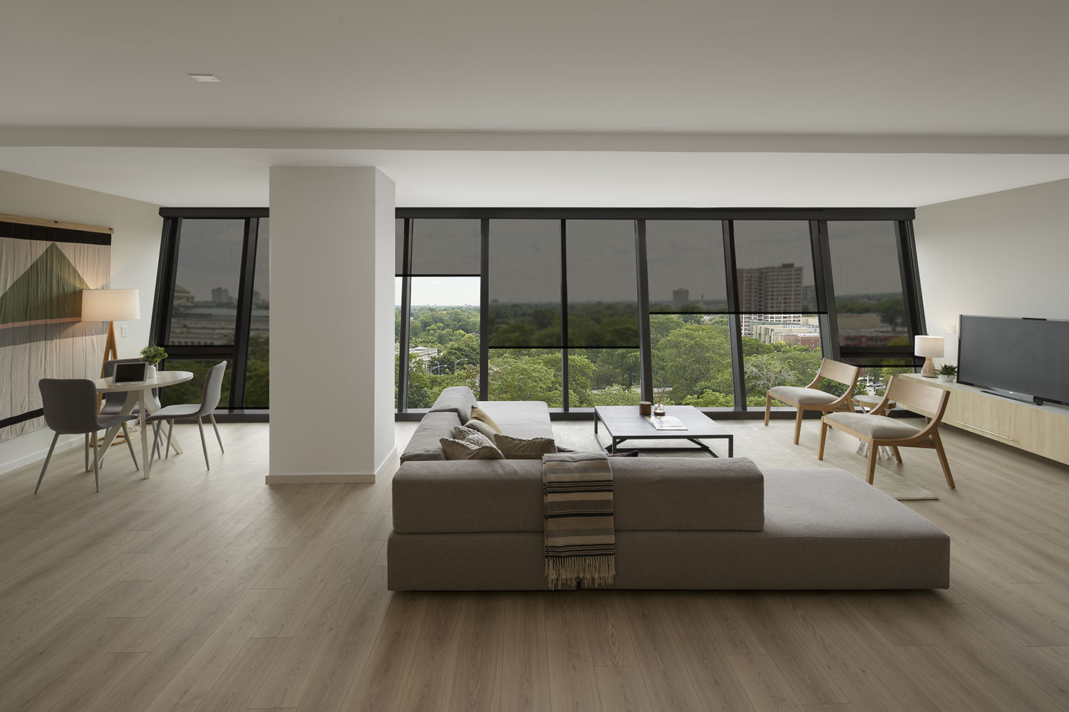 large open-plan living room with wood floors and angled glass windows in backhground