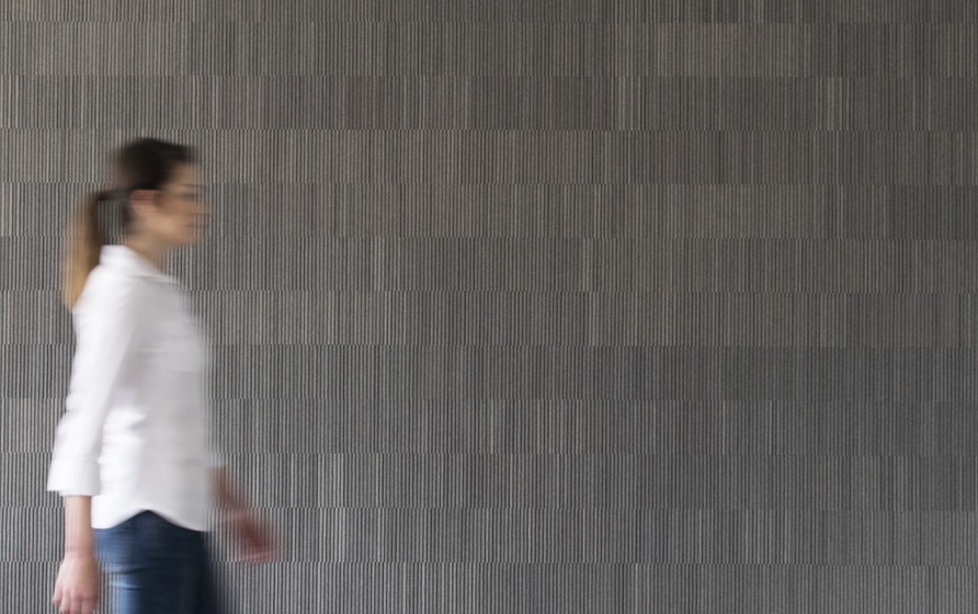 woman walking in front of charcoal wall with ribbed acoustical felt covering