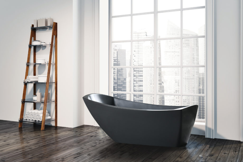 dark gray modern slipper bathtub in open bath in front of window looking out to highrises