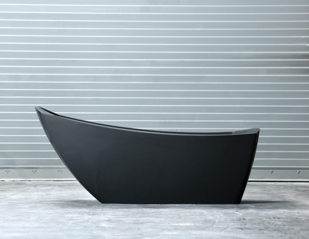 modern dark gray slipper bathtub on cement floor in front of gray wall