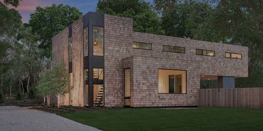 Modern Net Zero Hamptons' home with shingle siding in wooded envrionment