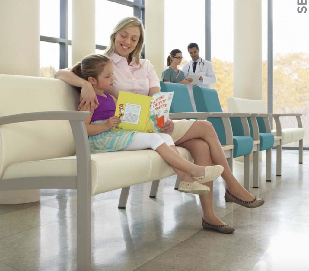 Primacare Seating Mother and child sitting and reading amid line of chairs alternating white and blue with doctor and nurse in the background