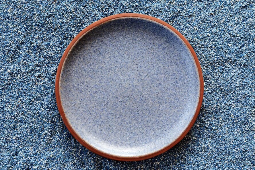 Granbyware close-up of large dinner plate in cobalt blue on top of blue crushed materials