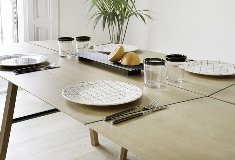 Woodendot's Savia Table partial view of table set for dinner with white plates and a cut orange