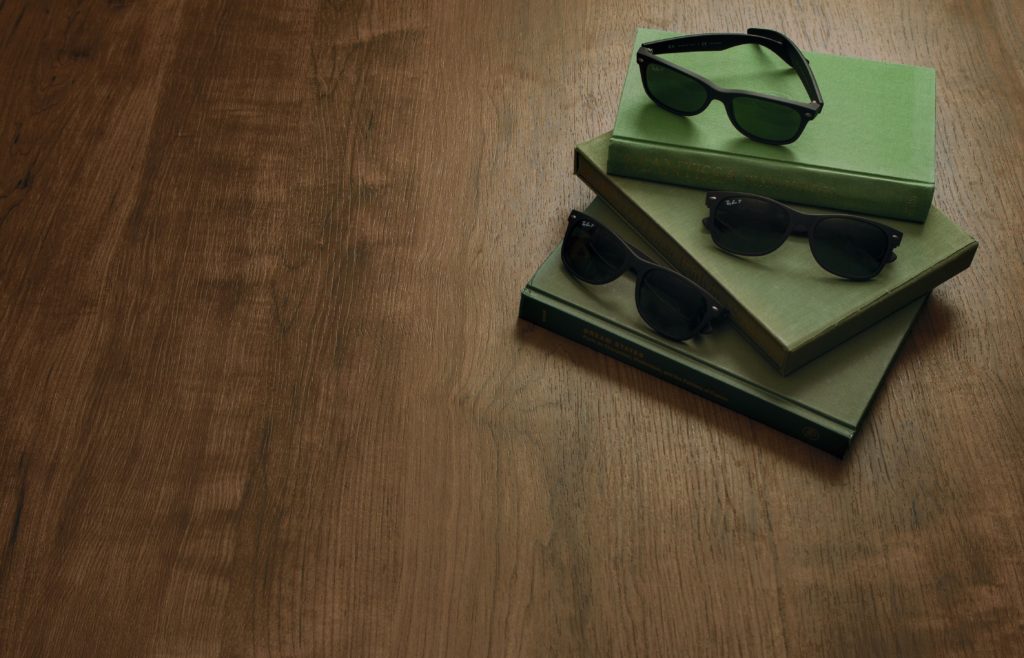 Wilsonart Color Me Intrigued maple with three green books and three pairs of sunglasses