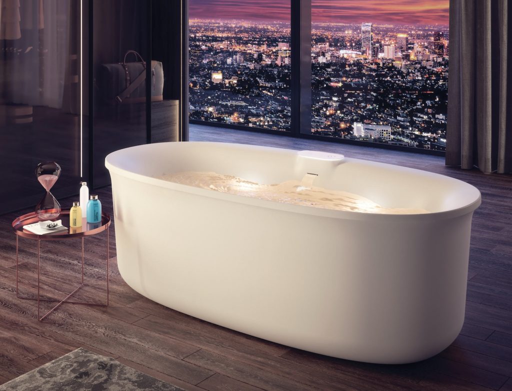 Jacuzzi's Arga bathtub in open apartment with nighttime view of city visible through window
