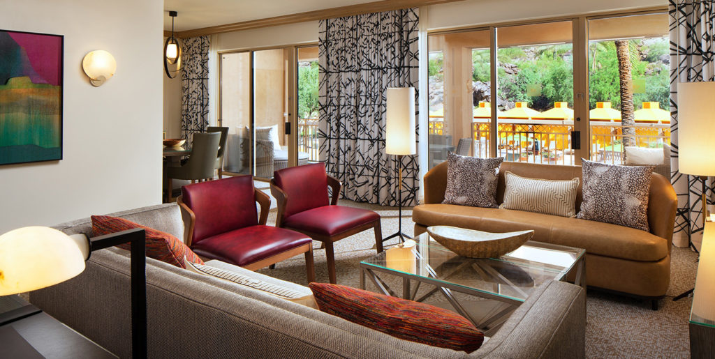 Demar Leather Canyon Suites Scottsdale sofas and chairs in grey, pomegranate and, buff upholstery in lounge area with palm trees visible through window
