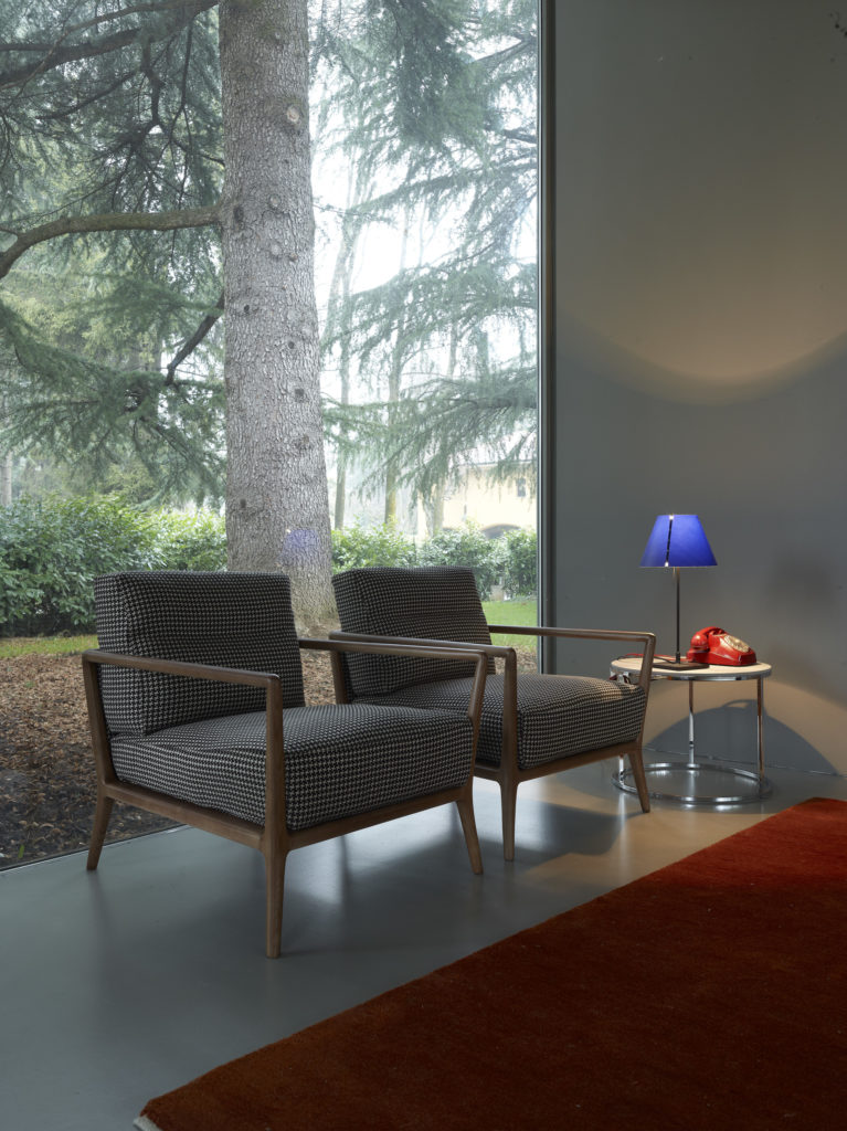 Carlton Armchair for Nube two chairs side by side in front of large window in modern home with forest visible beyond