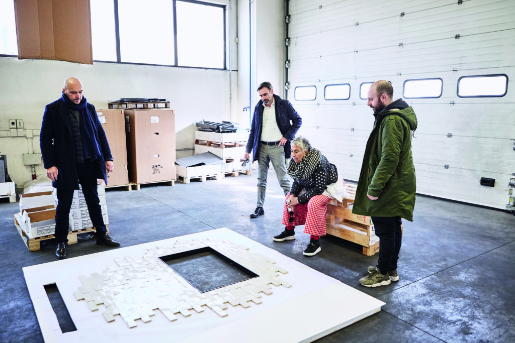 MCZ Fireplace Cladding production shot with Paola Navone examining prototype in warehouse with three men standing around