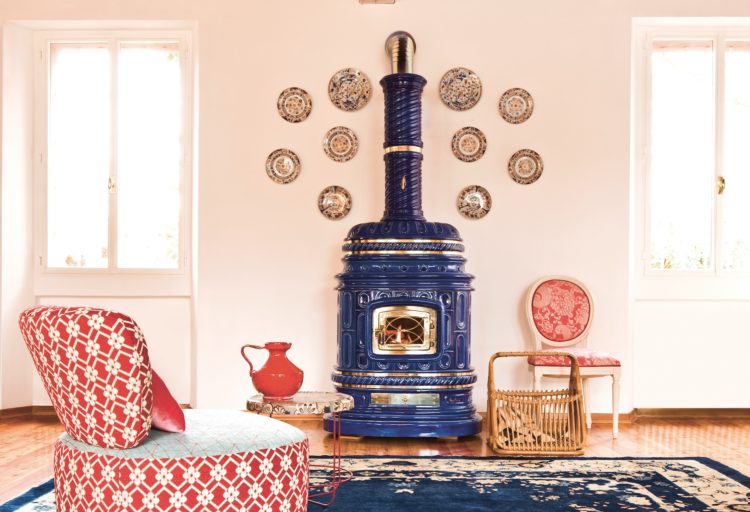 Corsara Stove front view medium with stove in ornate room with pink/white divan, pink/white chairs, luxurious blue patterned rug and gold platters on wall behind stove