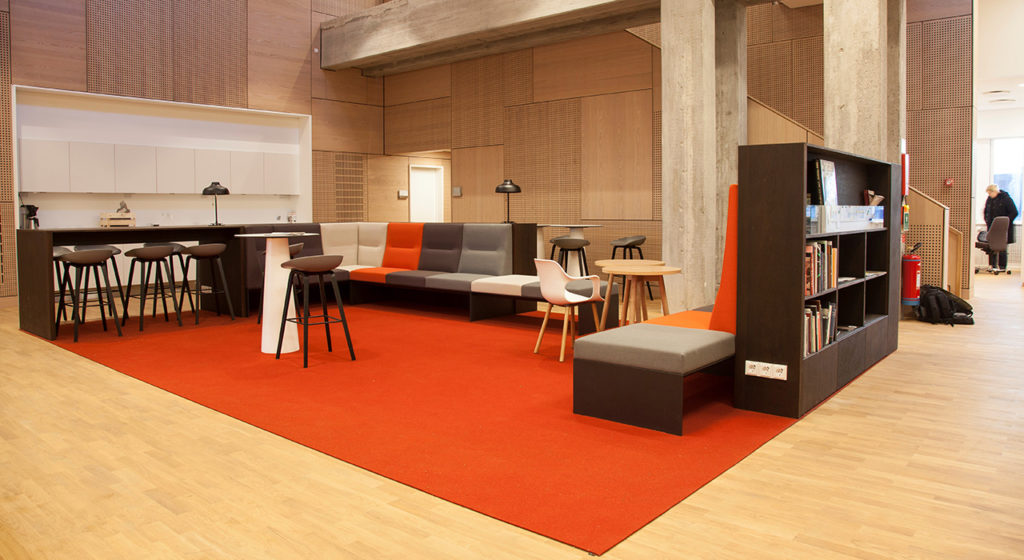 Fraster Felt Rug Collection large orange rug in workspace with modular seating and tall table with light wood floors