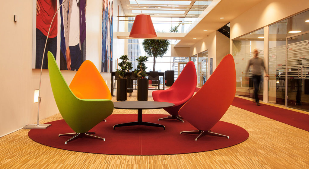 Fraster Felt Rug Collection round red rug with colorful cone-shaped chairs on it in open office/reception area