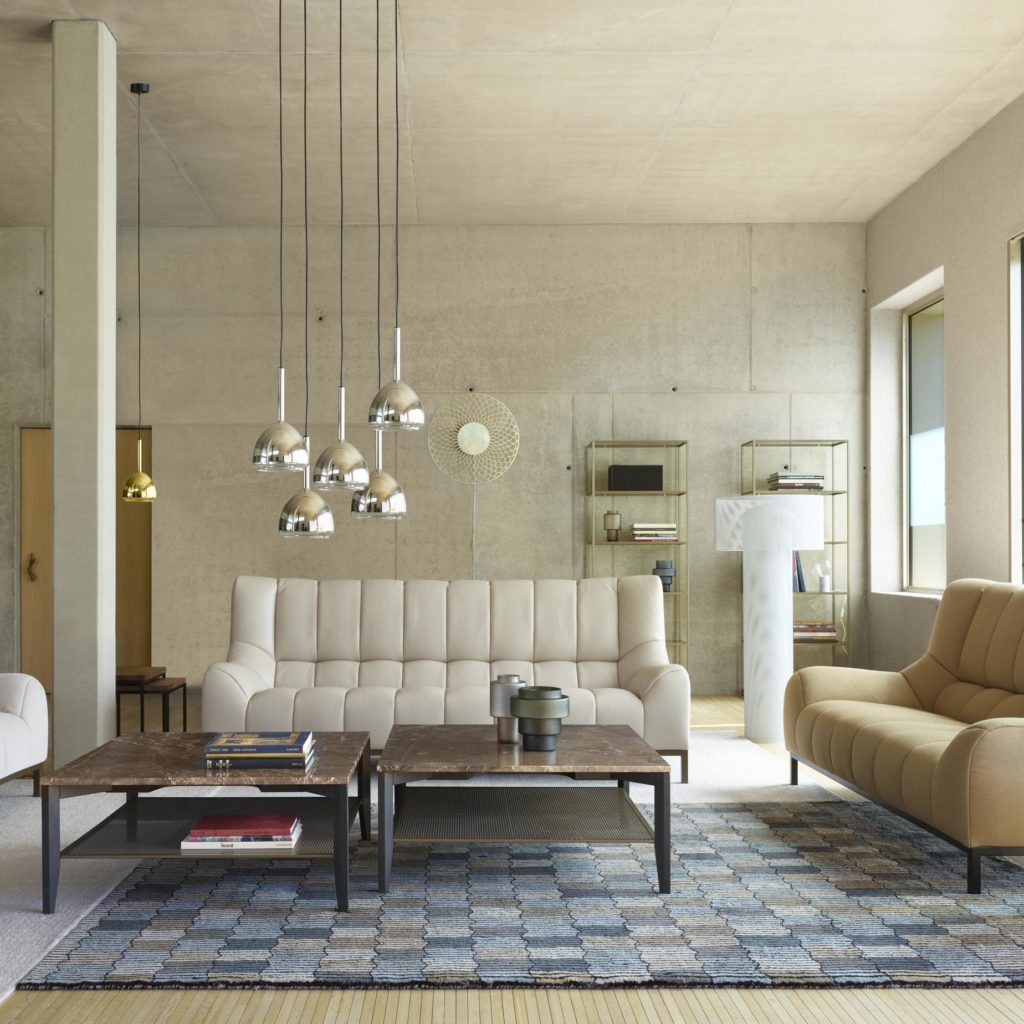 Ligne Roset Phileas Sofa large light gray in fancy living room with adjacent mustard colored loveseat, white walls, and low-hanging pendant lamp with chrome shades