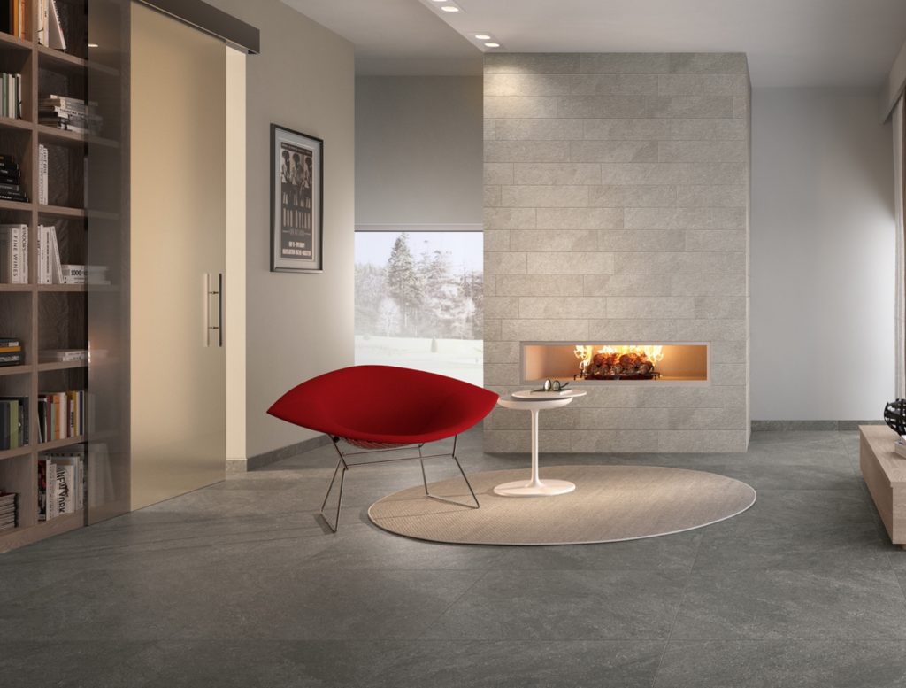 Art of Simplicity tile Alta style on floor and wall in gray/white palette in nice living room with fireplace, bookshelf, and modern red chair