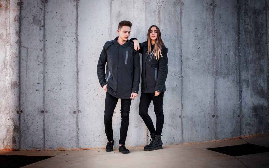 Ultra Coat worn by a man and woman model in front of cement wall