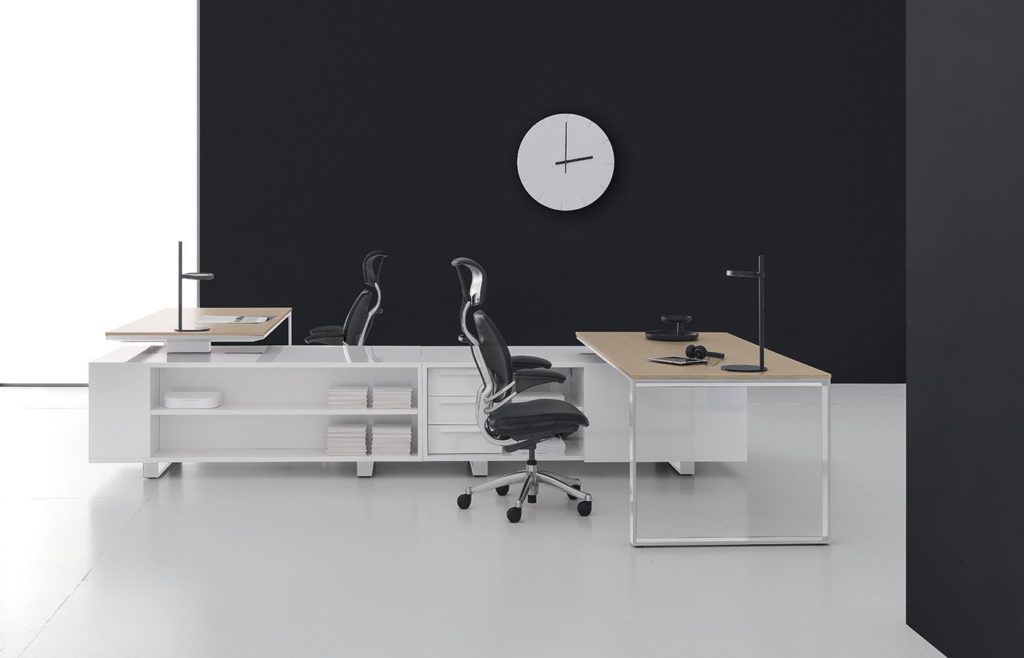 DVO Executive Office Planeta twin worktables and storage  with twin black task chairs in modern office with black wall and large white clock 