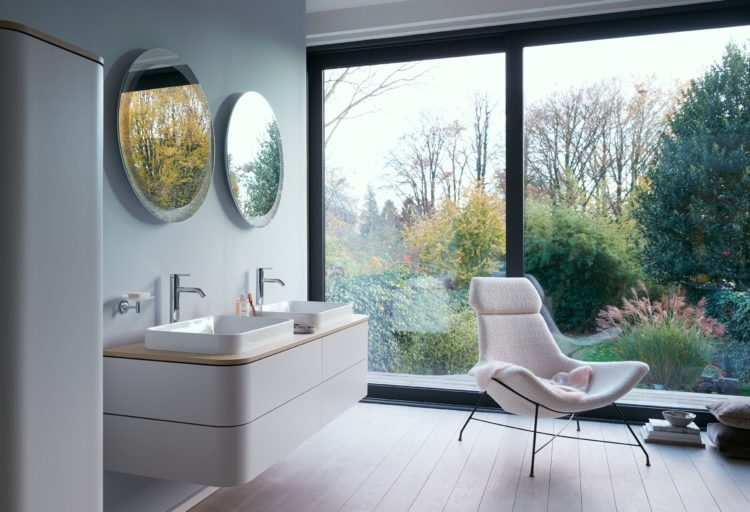 Happy D Happy D.2 Plus white console in nice bathroom with pink chair and sliding glass door to forest outside