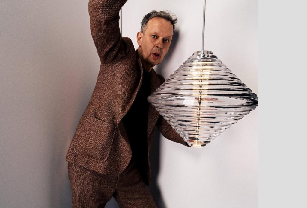 Tom Dixon Press Light in the shape of a spinning top with Dixon holding it