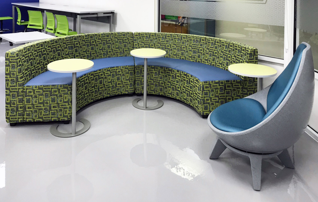 KI C-Table Max round with cream top and silver leg and base next to modular curved lounge and futuristic chair 