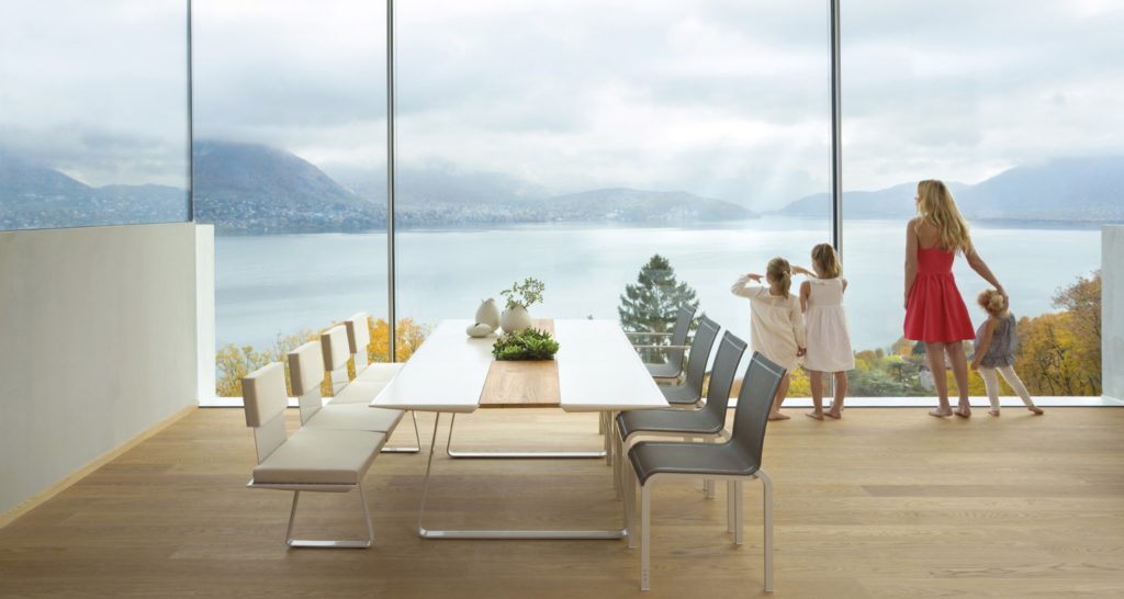 Extrados table in open room with view of lake and mountains and a family with mother and three daughters