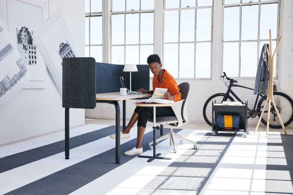 Teknion Routes woman working at double desk with privacy screen in sunny office 