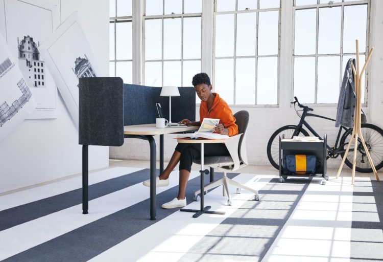 Teknion Routes woman working at double desk with privacy screens in sunny office