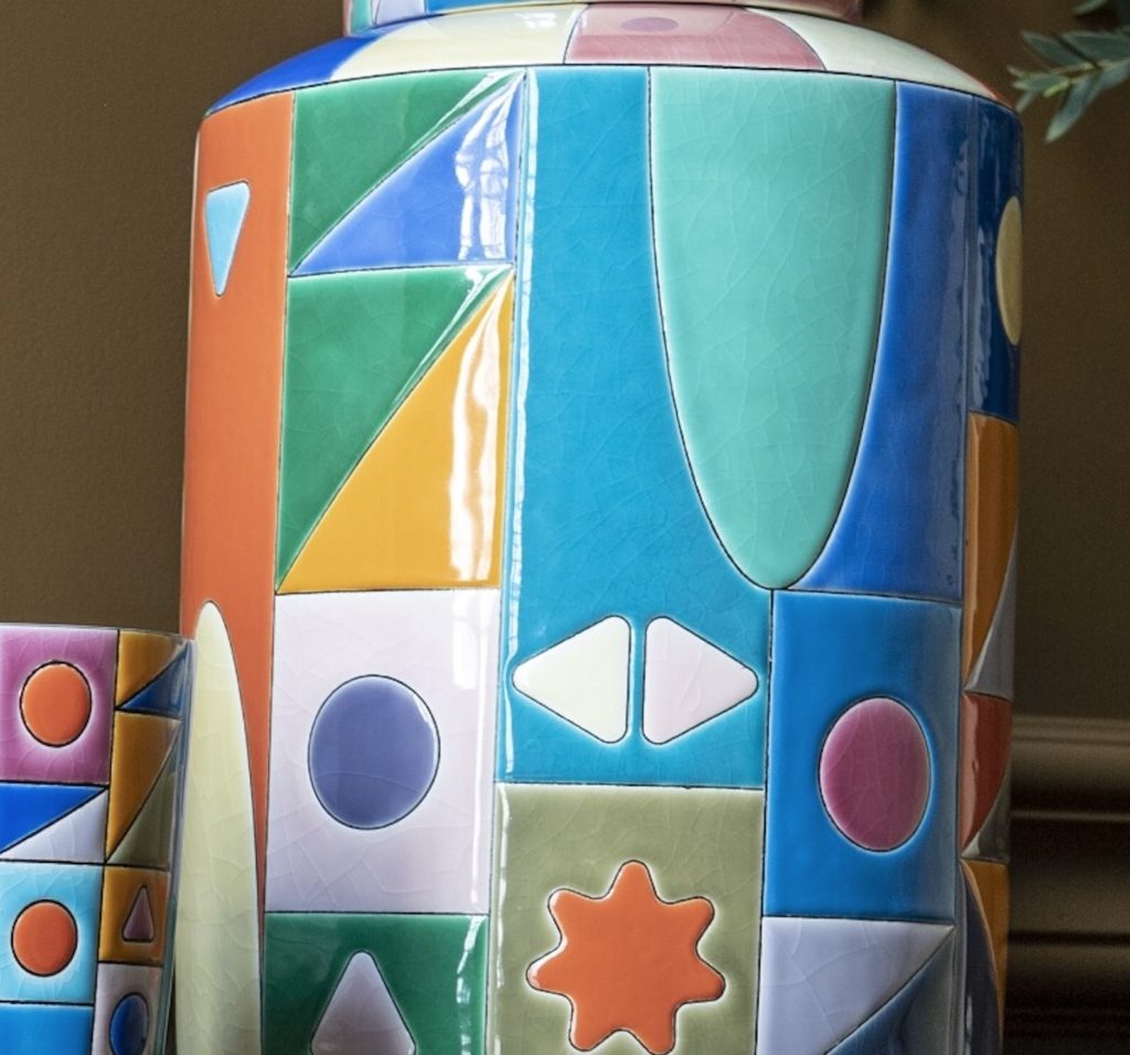 Enameed jar with many colors in squares and rectangles and different shapes within the squares 