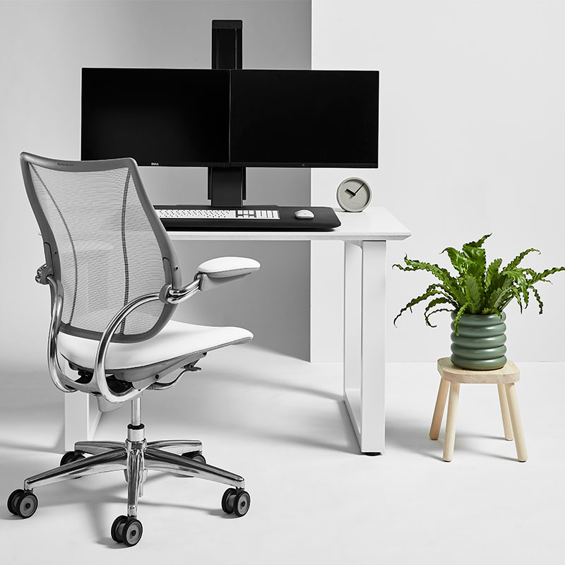 QuickStand Eco front view with dual monitor on white desk with white chair next to plant