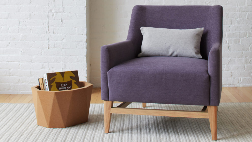 A comfy chair upholstered in purple fabric in a nice light room 