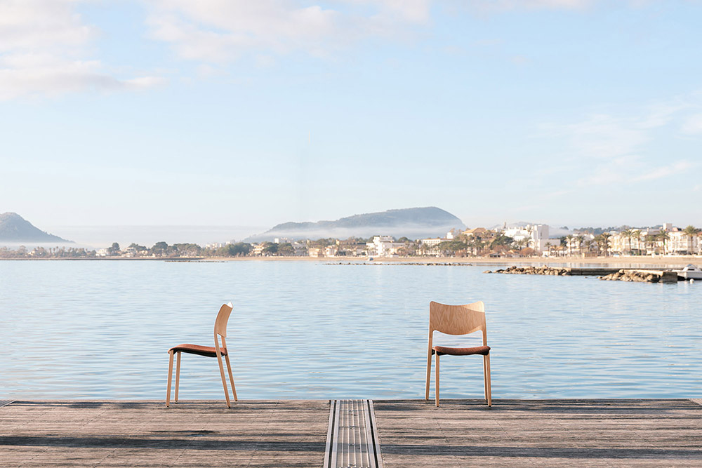 chairs on dock in tropical bay with mountains in background